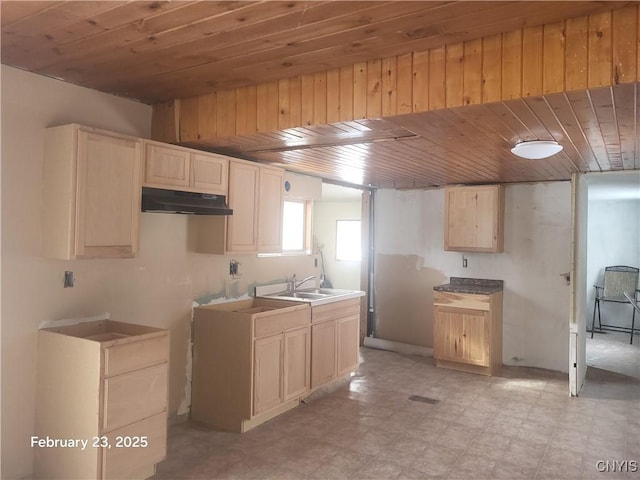 kitchen with light brown cabinets, under cabinet range hood, light floors, wood ceiling, and a sink