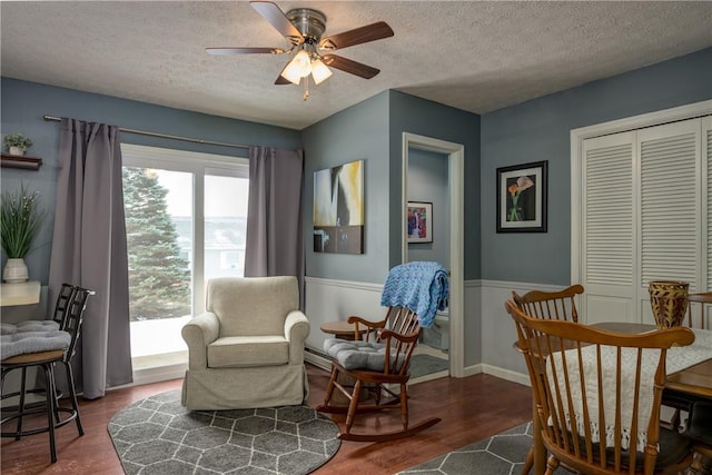 living area featuring baseboards, a textured ceiling, wood finished floors, and a ceiling fan