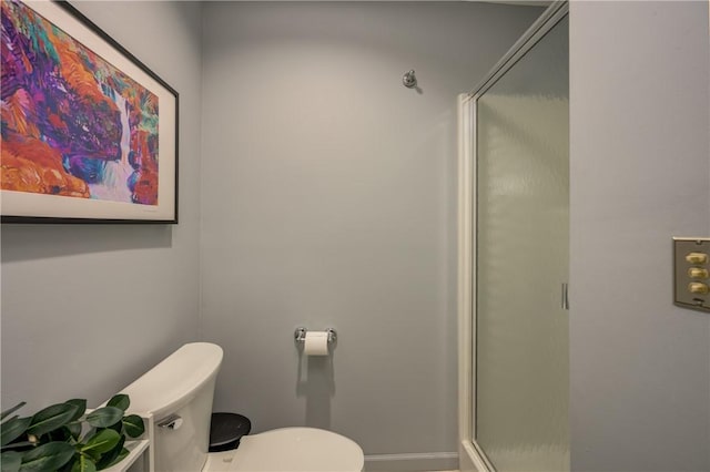 bathroom featuring a shower stall, toilet, and baseboards