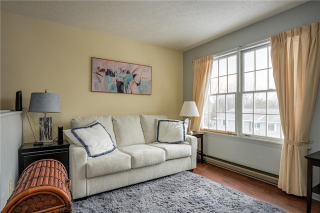 living room featuring a baseboard heating unit, a textured ceiling, and wood finished floors