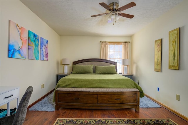 bedroom featuring baseboards, dark wood-type flooring, a ceiling fan, and a textured ceiling