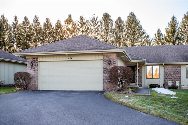 single story home featuring brick siding, a front lawn, roof with shingles, a garage, and driveway