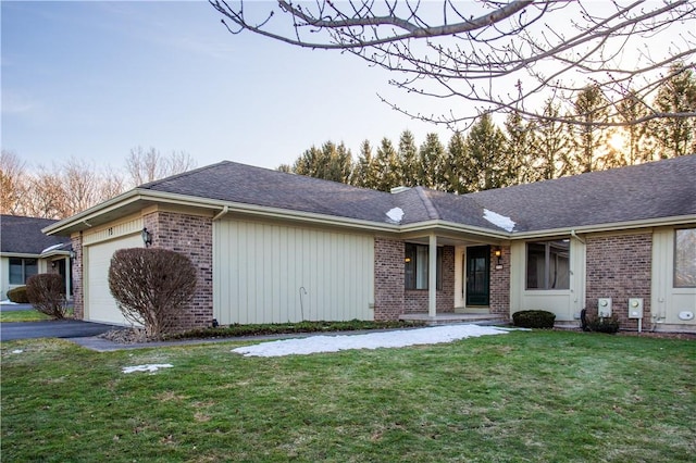 single story home featuring driveway, a shingled roof, a front lawn, a garage, and brick siding