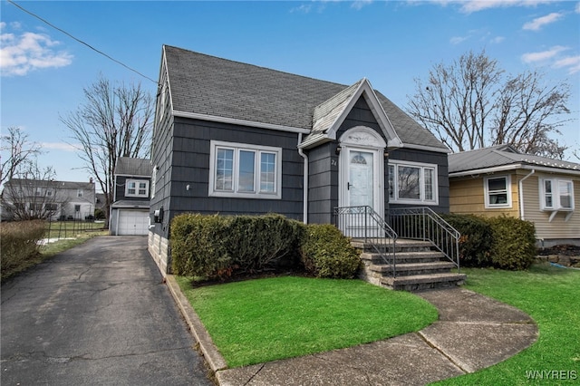 view of front of property featuring a front lawn and roof with shingles