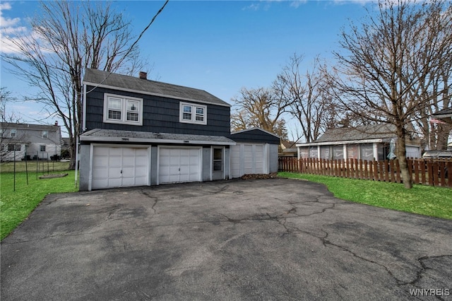 exterior space featuring fence, driveway, a chimney, a front lawn, and a garage