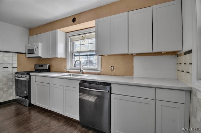 kitchen with white cabinets, stainless steel appliances, light countertops, and a sink