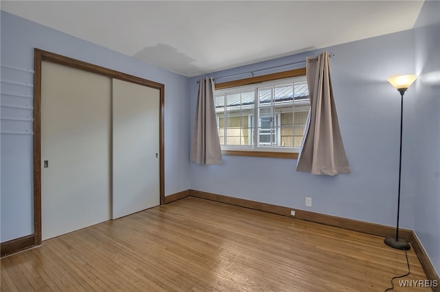 unfurnished bedroom featuring baseboards, a closet, and light wood finished floors