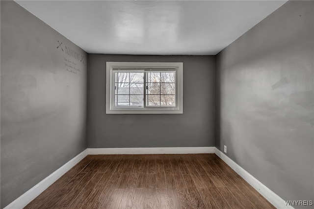 unfurnished room with baseboards and dark wood-style floors