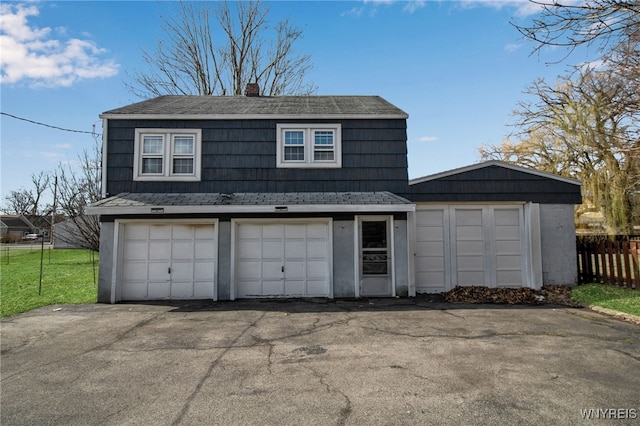 garage with aphalt driveway and fence