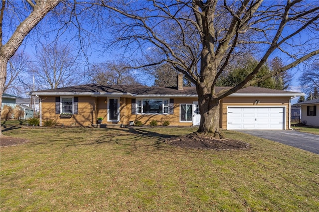 single story home featuring aphalt driveway, an attached garage, a front yard, and a chimney