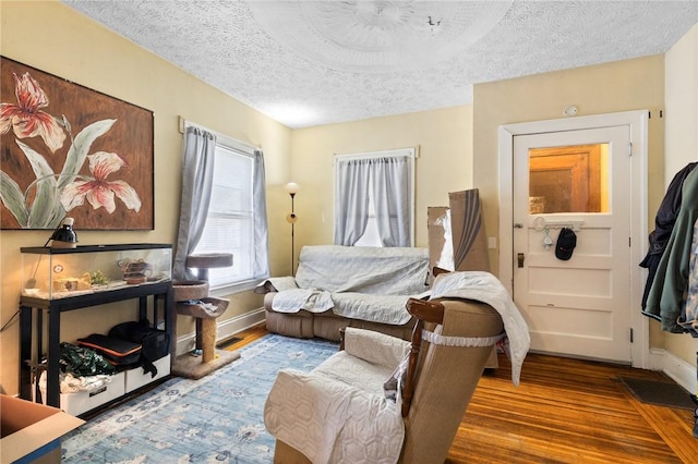living area with visible vents, wood finished floors, baseboards, and a textured ceiling