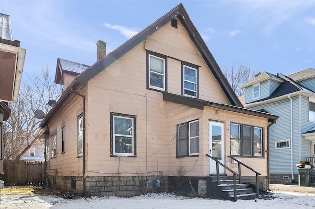 view of front of home featuring fence, a chimney, and entry steps