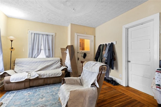 living area featuring a textured ceiling, baseboards, and wood finished floors