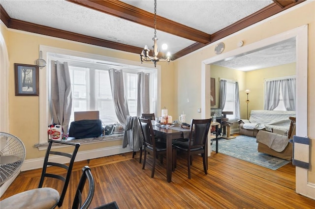 dining area featuring an inviting chandelier, ornamental molding, wood finished floors, and a textured ceiling