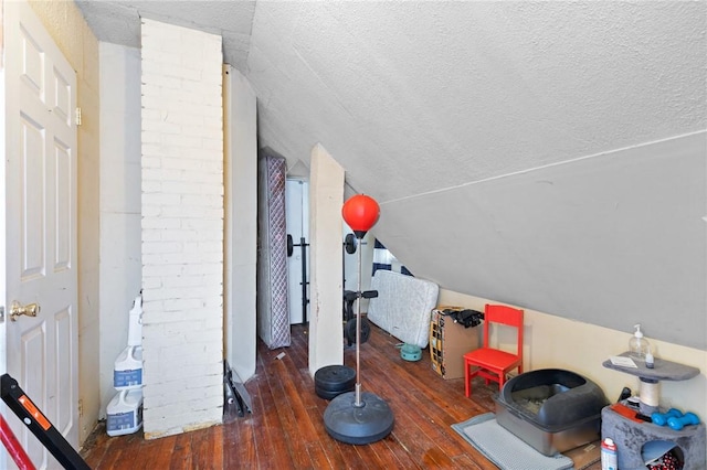 additional living space featuring vaulted ceiling, a textured ceiling, and hardwood / wood-style flooring