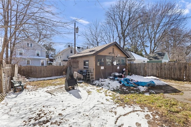 snow covered house with an outbuilding and a fenced backyard