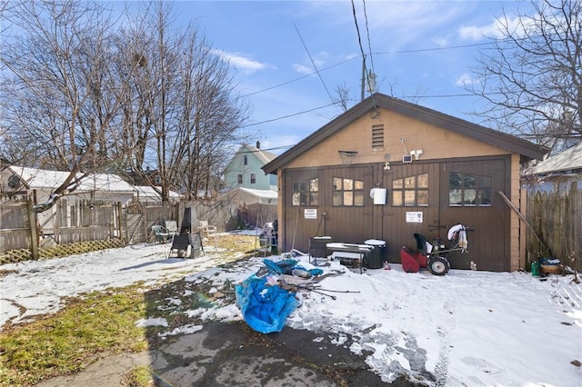 snow covered house featuring an outbuilding and fence