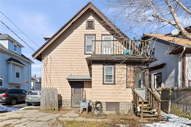 view of front of house with a balcony, entry steps, and fence