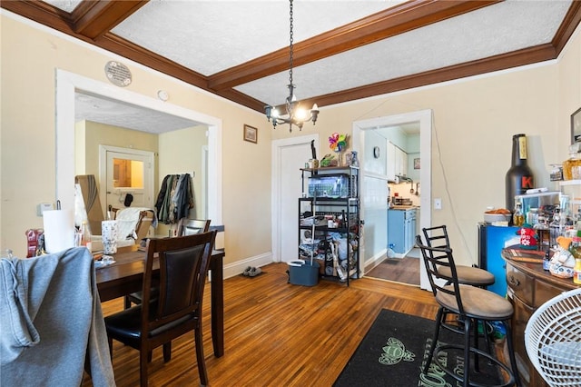 dining area featuring crown molding, baseboards, beamed ceiling, an inviting chandelier, and wood finished floors
