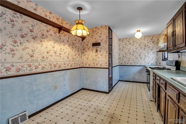 kitchen featuring visible vents, wallpapered walls, a wainscoted wall, gas range, and light floors