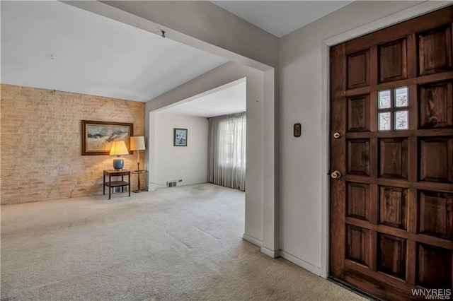 foyer with visible vents, brick wall, baseboards, and carpet