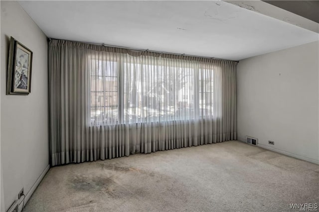 spare room with carpet, visible vents, and a wealth of natural light