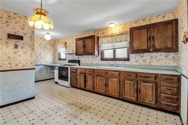 kitchen with white gas range, light floors, wallpapered walls, and a sink