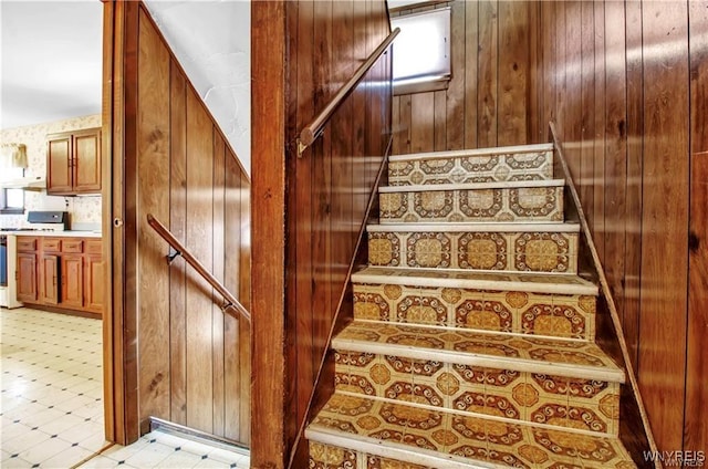 stairway with tile patterned floors and wooden walls