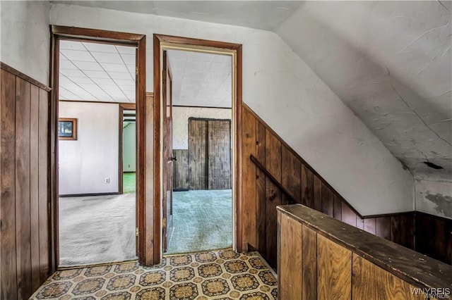 hall featuring lofted ceiling and wooden walls