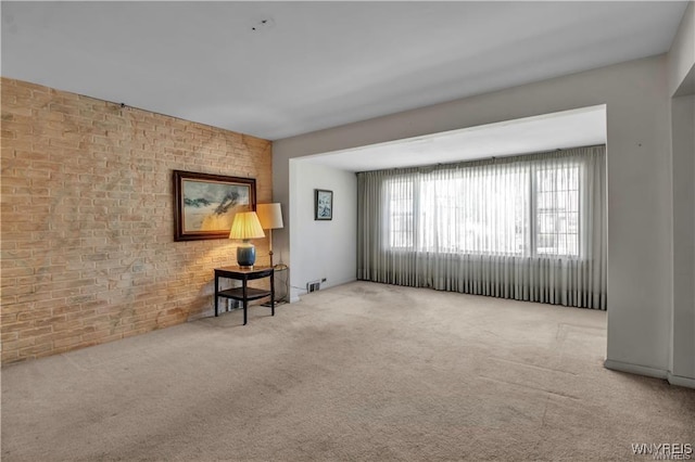 carpeted spare room with brick wall