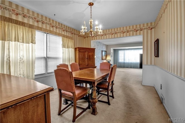 dining room featuring a chandelier, light colored carpet, and wallpapered walls