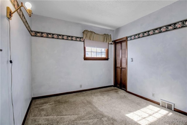 empty room with visible vents, baseboards, a textured ceiling, and carpet flooring