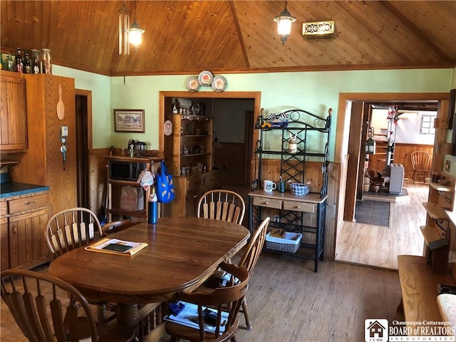 dining room featuring a wainscoted wall, wood walls, wood ceiling, lofted ceiling, and wood finished floors