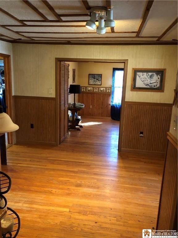 interior space with light wood-style floors, wood walls, and wainscoting