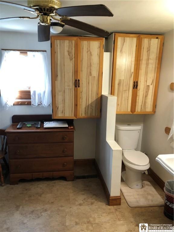 bathroom featuring baseboards, toilet, and ceiling fan