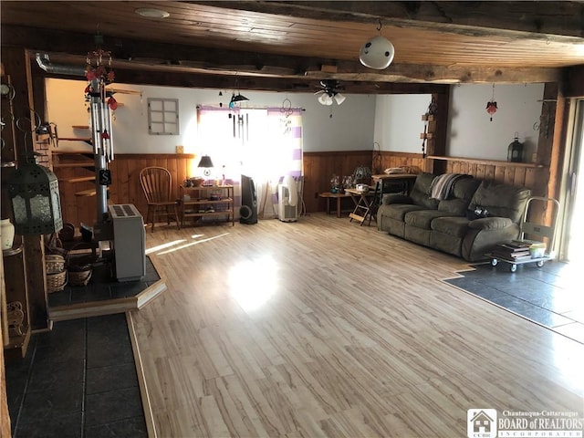 living area with a wainscoted wall, beam ceiling, wood ceiling, and wood finished floors