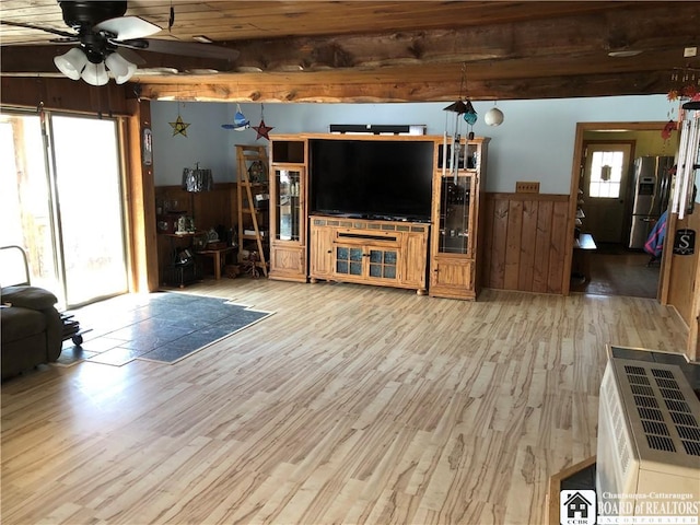 living area featuring a wainscoted wall, heating unit, wood finished floors, wood walls, and ceiling fan