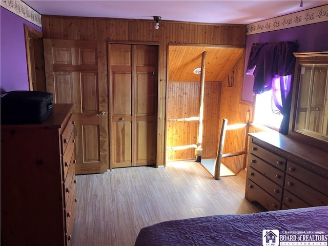 bedroom with wooden walls and light wood-type flooring