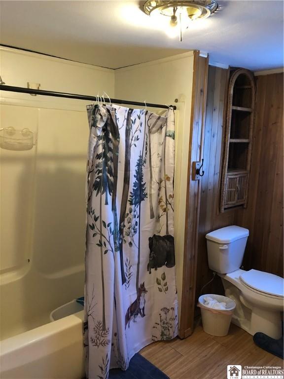 full bath featuring shower / bathtub combination with curtain, toilet, and wood finished floors