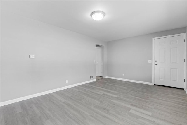 spare room with visible vents, baseboards, and wood finished floors