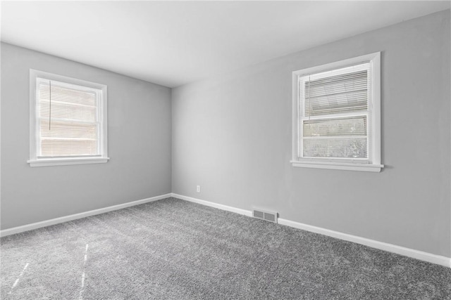 carpeted spare room featuring visible vents and baseboards