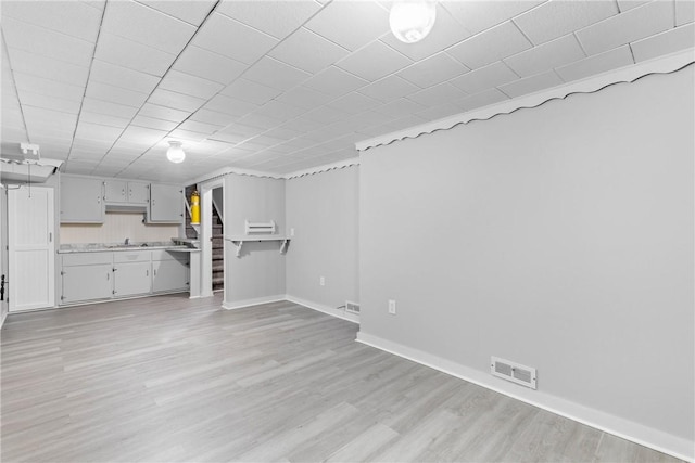 interior space with light countertops, baseboards, visible vents, and light wood-type flooring