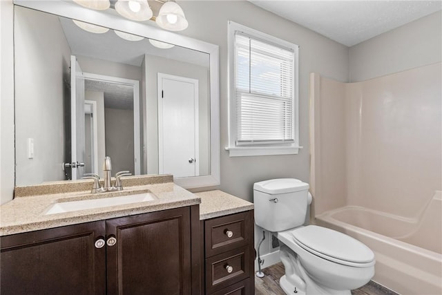 full bath with washtub / shower combination, toilet, wood finished floors, and vanity