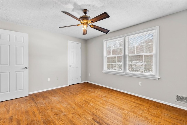 unfurnished room with visible vents, a textured ceiling, light wood finished floors, baseboards, and ceiling fan