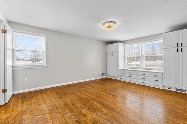 unfurnished bedroom featuring a textured ceiling, baseboards, and wood finished floors