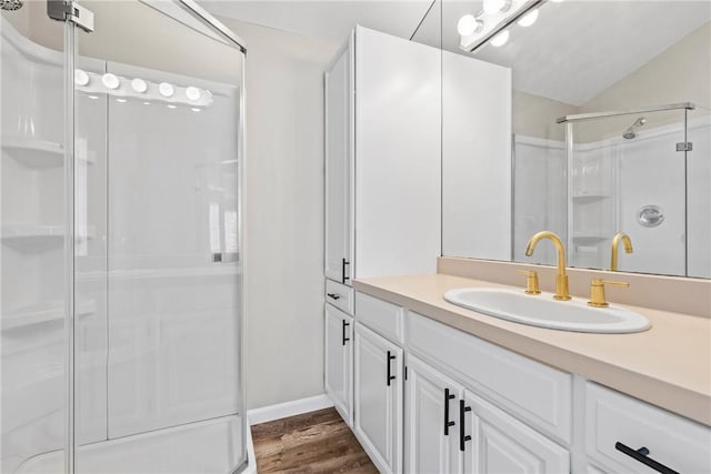 bathroom with vanity, a shower stall, wood finished floors, and vaulted ceiling