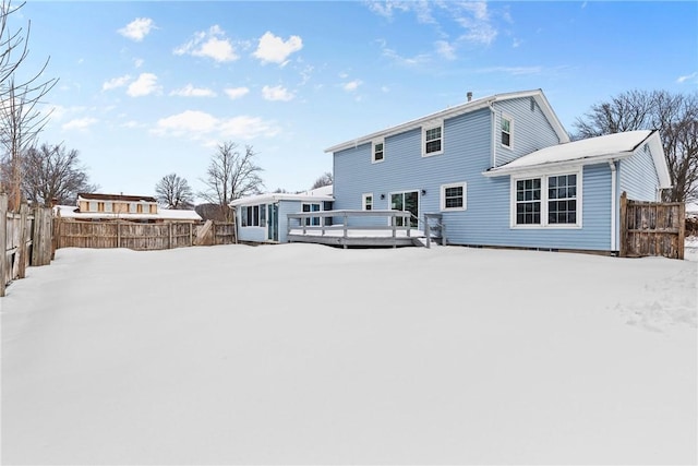 snow covered house featuring a deck and a fenced backyard