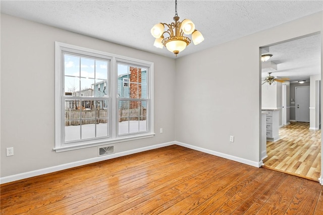 spare room with visible vents, baseboards, a textured ceiling, and hardwood / wood-style flooring