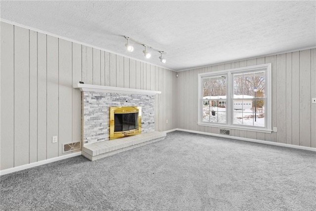 unfurnished living room featuring baseboards, visible vents, a fireplace, a textured ceiling, and carpet flooring