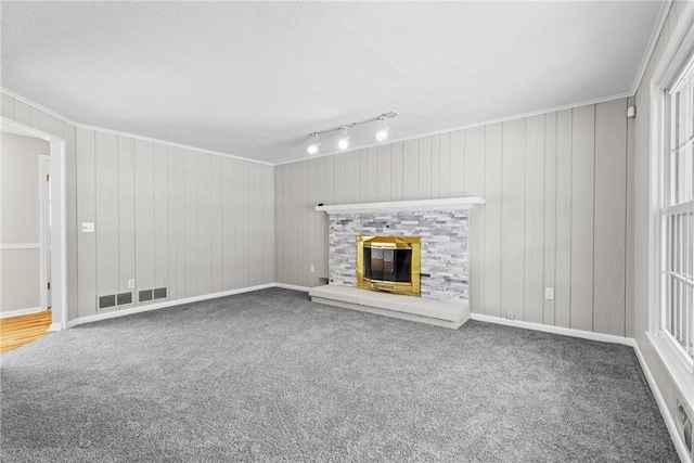 unfurnished living room featuring visible vents, carpet floors, a glass covered fireplace, and crown molding